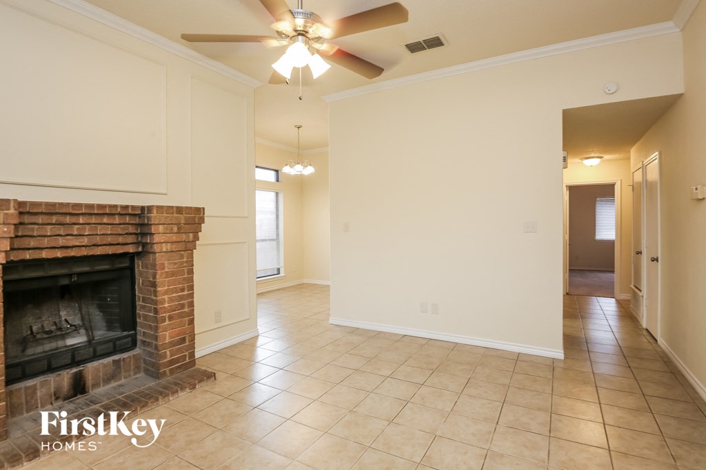 a living room with a brick fireplace and a ceiling fan