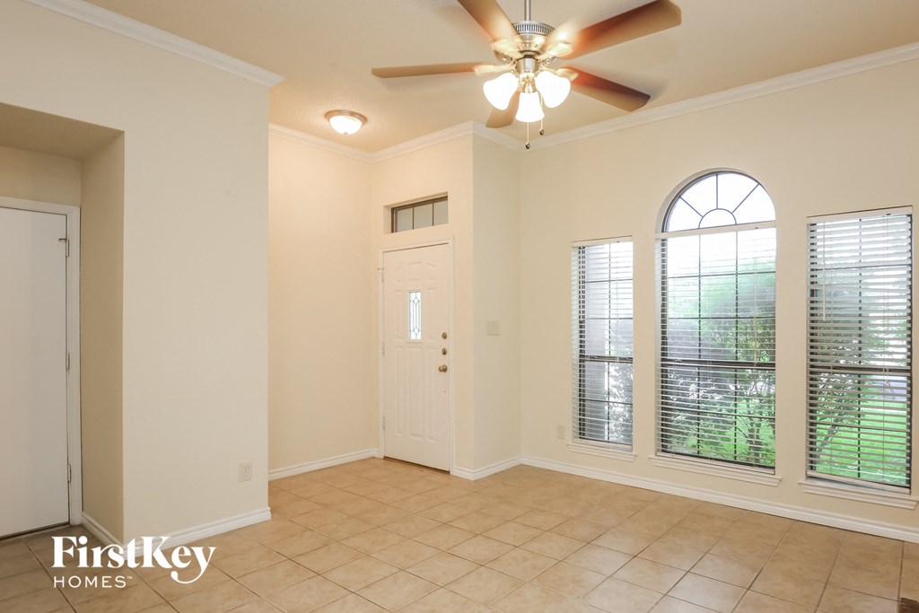 an empty living room with a ceiling fan and windows