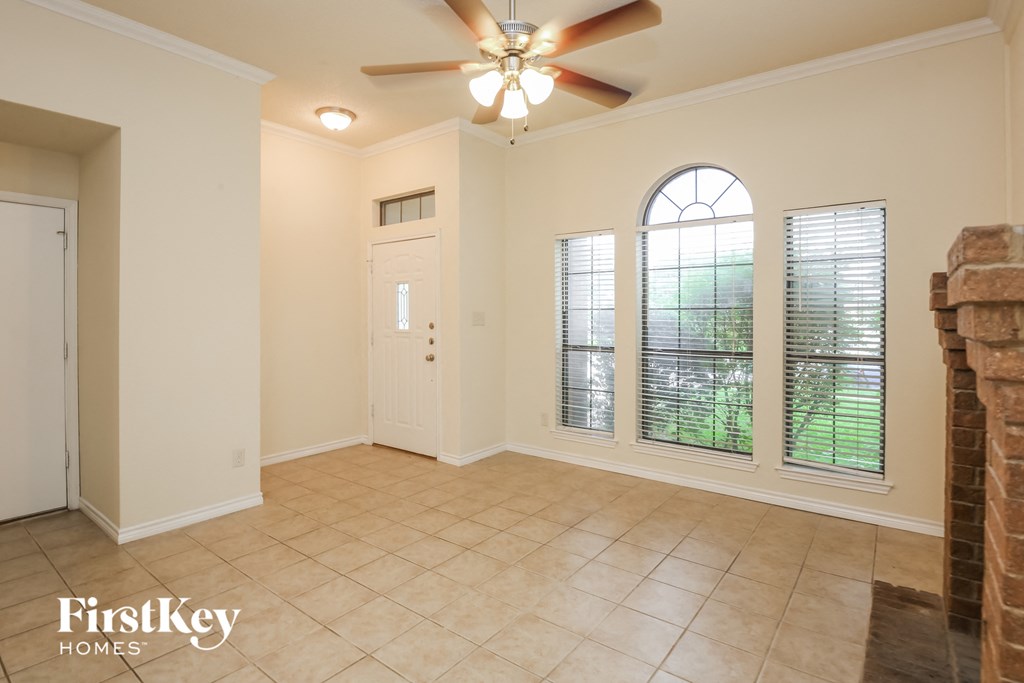 an empty living room with a ceiling fan and windows