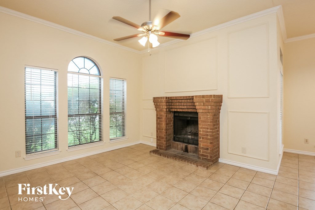 a living room with a brick fireplace and a ceiling fan