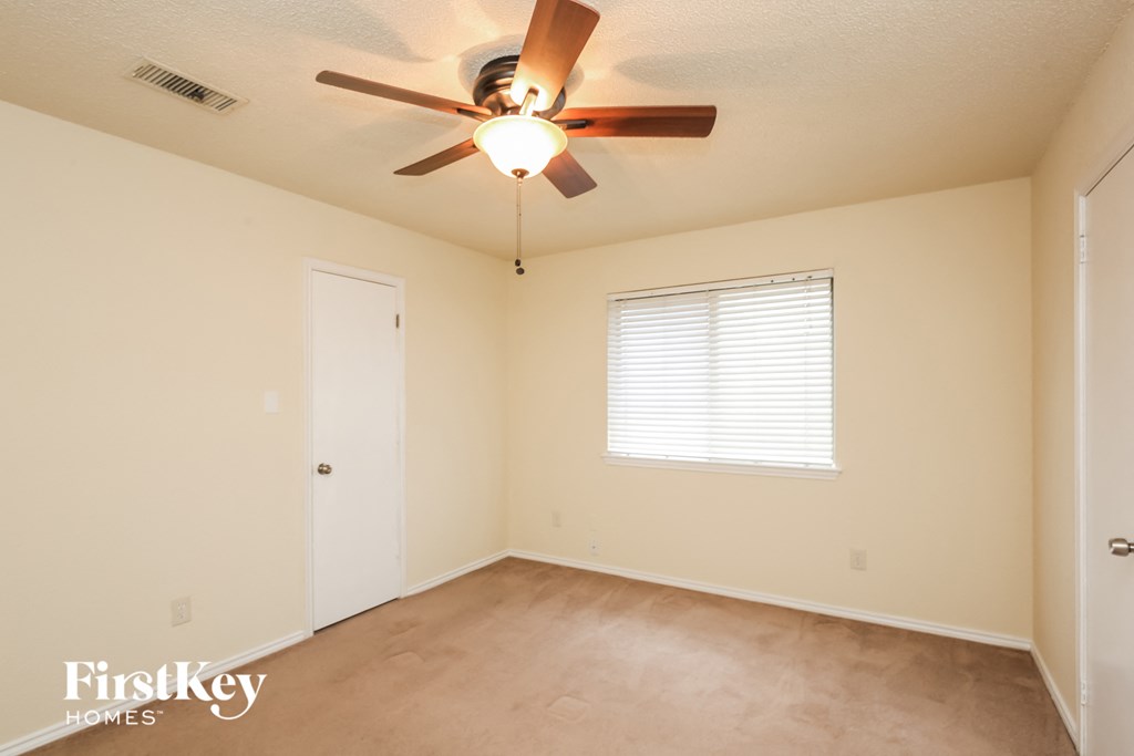 the living room of an empty home with a ceiling fan
