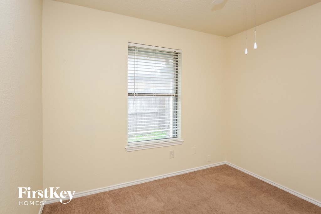 a bedroom with a window and a carpeted floor