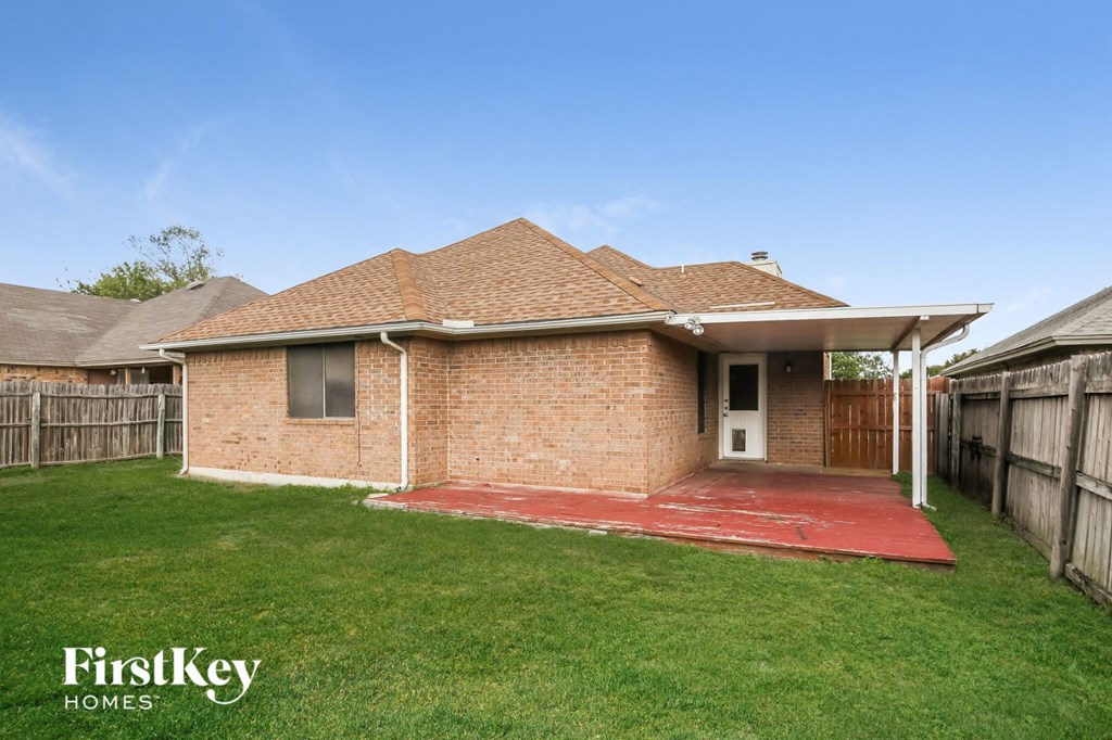 a small brick house with a yard and a wooden fence