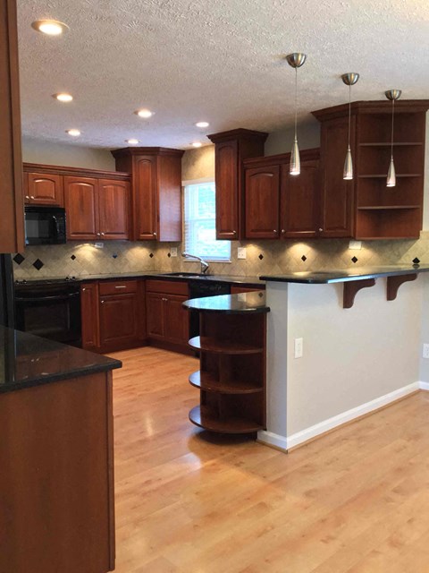 A kitchen with wooden cabinets and a black counter top.