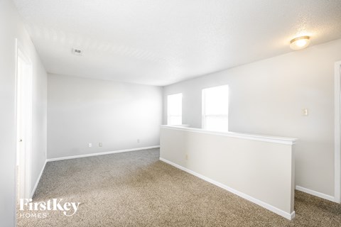 a spacious living room with carpet and white walls