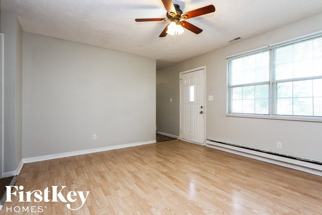 A room with a ceiling fan and wooden flooring.