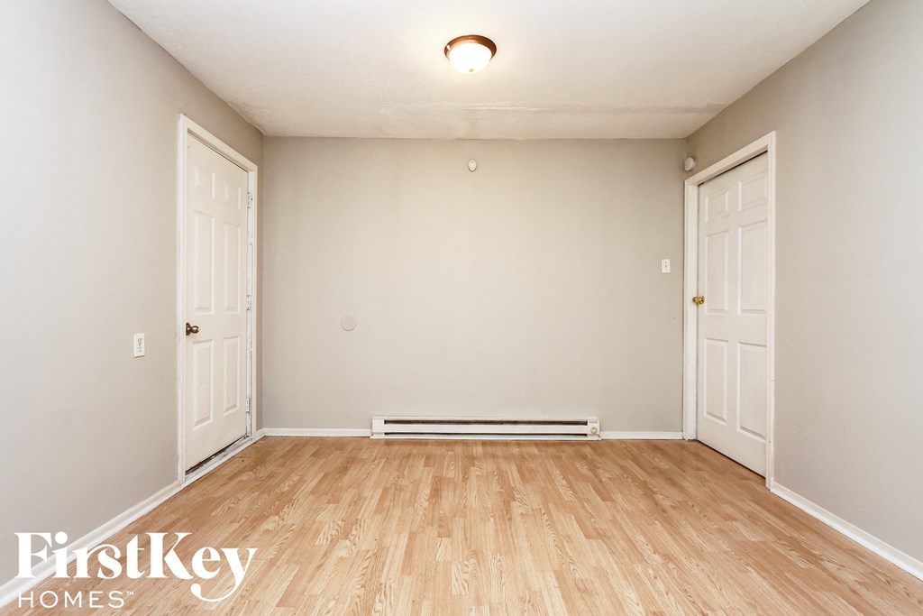 A room with wooden flooring and two white doors.