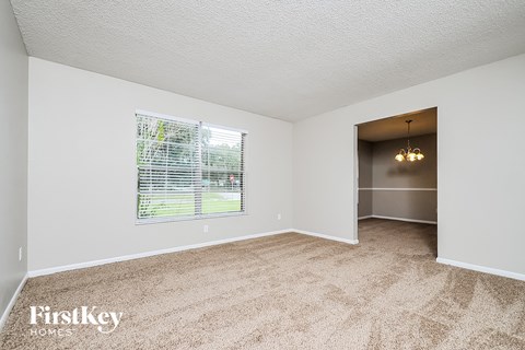 A room with a carpeted floor and a window with blinds.