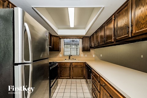 A kitchen with wooden cabinets and a stainless steel refrigerator.