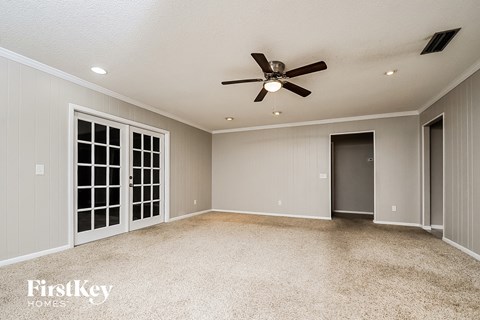 A spacious room with a ceiling fan and a carpeted floor.
