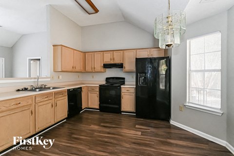 a kitchen with wooden cabinets and black appliances and a chandelier