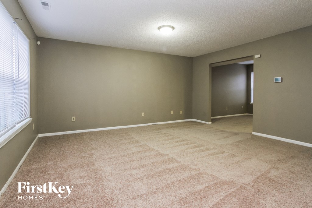 A room with a carpeted floor and a door on the right side.