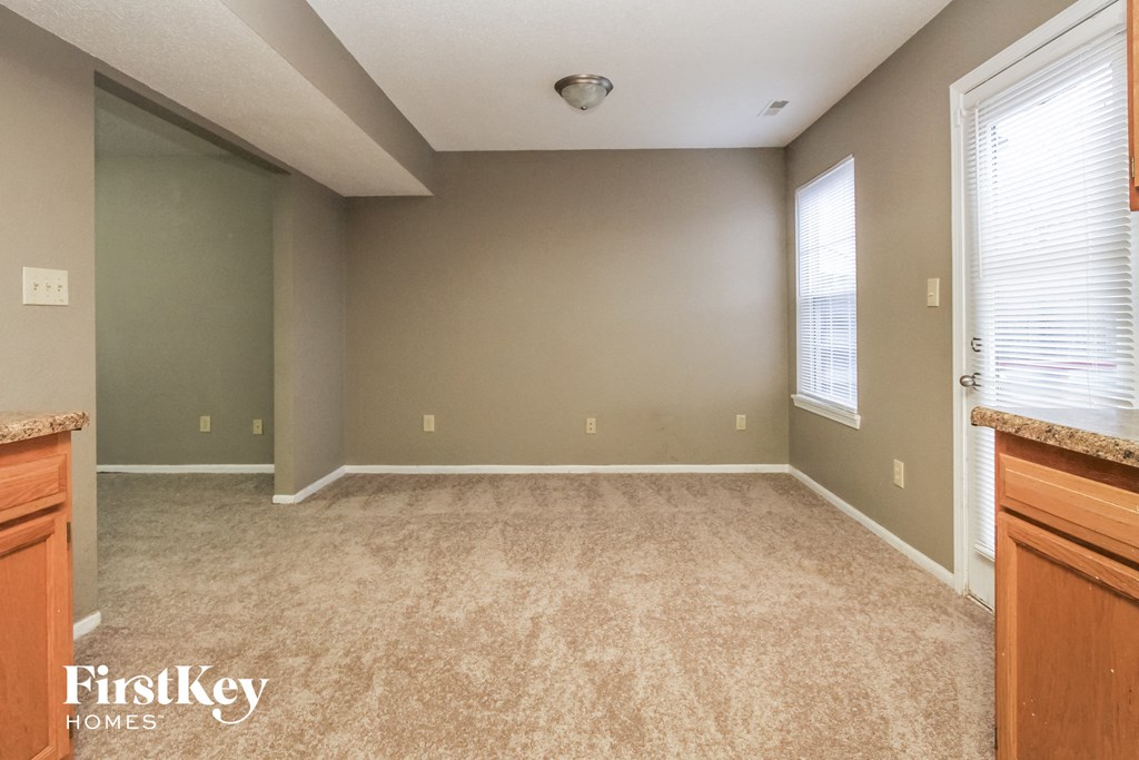 A room with a carpeted floor and a window with blinds.