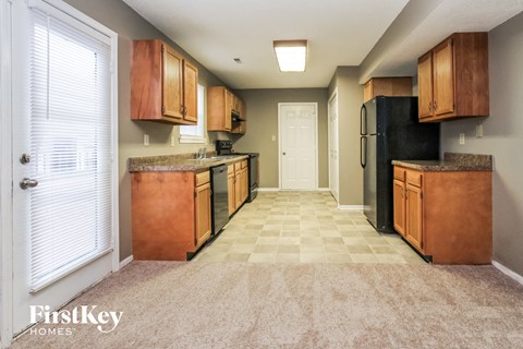 A kitchen with wooden cabinets and a black refrigerator.