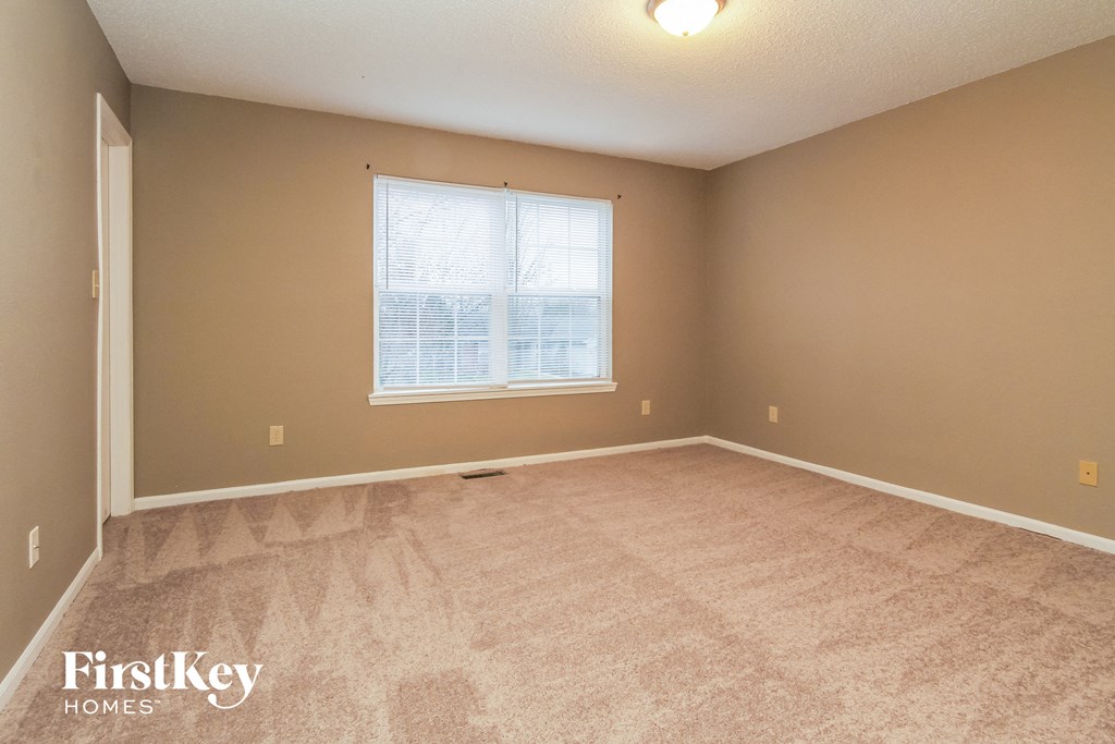 A room with a carpeted floor and a window with blinds.