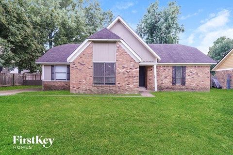 A brick house with a grassy front yard.