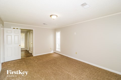 A spacious room with a carpeted floor and a doorway leading to another room.
