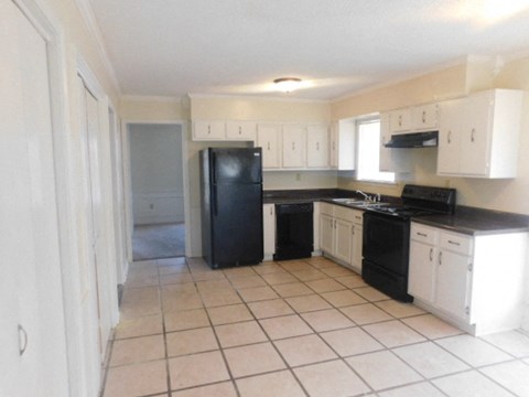 A kitchen with black appliances and white cabinets.