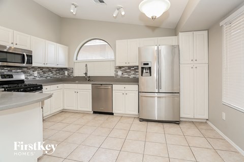 A kitchen with white cabinets and a stainless steel refrigerator.