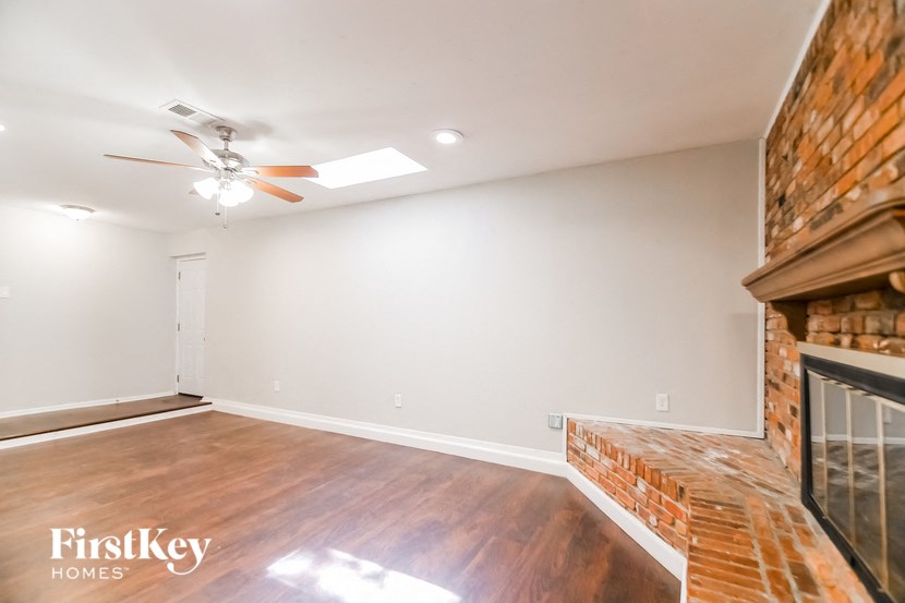 an empty living room with a fireplace and a ceiling fan