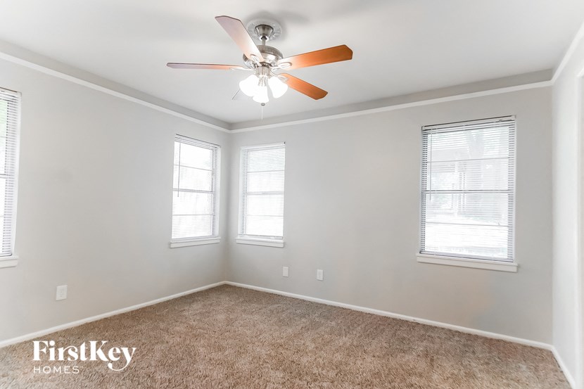 an empty room with a ceiling fan and two windows