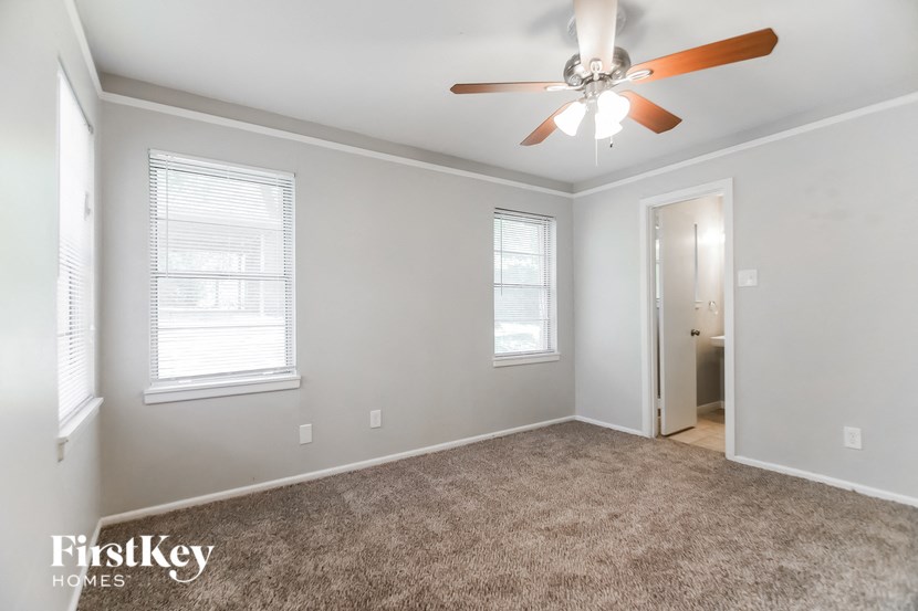 a living room with a ceiling fan and a carpet
