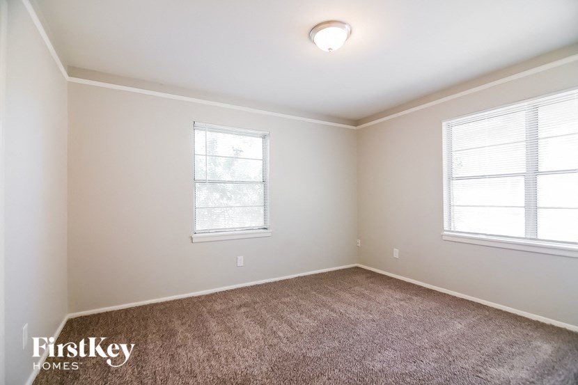 a bedroom with a carpeted floor and two windows