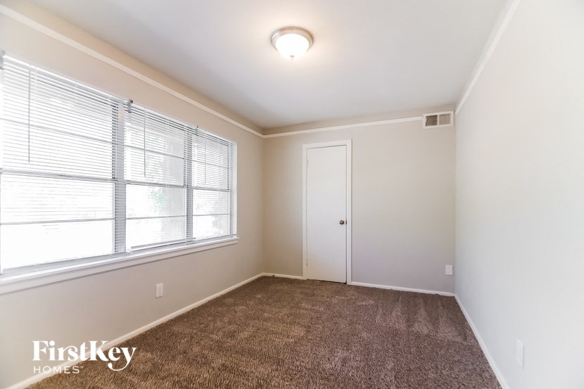a bedroom with a carpeted floor and a large window