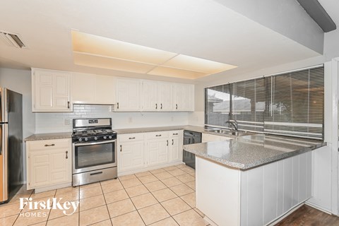 A kitchen with white cabinets and a stainless steel refrigerator.