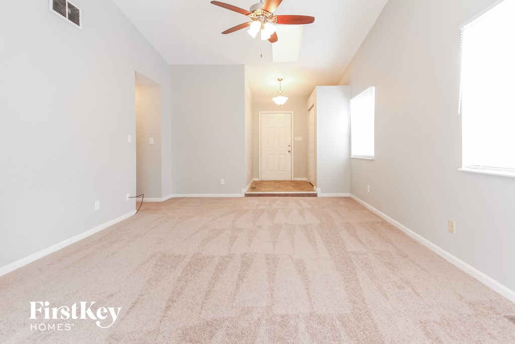a spacious living room with a ceiling fan and a carpeted floor