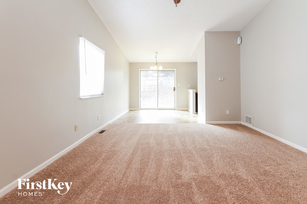 an empty living room with a carpeted floor and a window