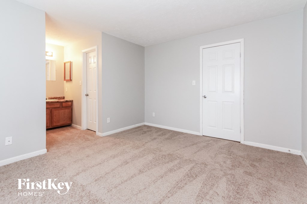 an empty living room with a white door and a bathroom