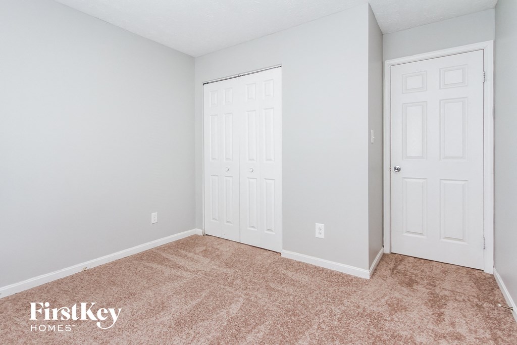 a bedroom with two closet doors and a carpeted floor