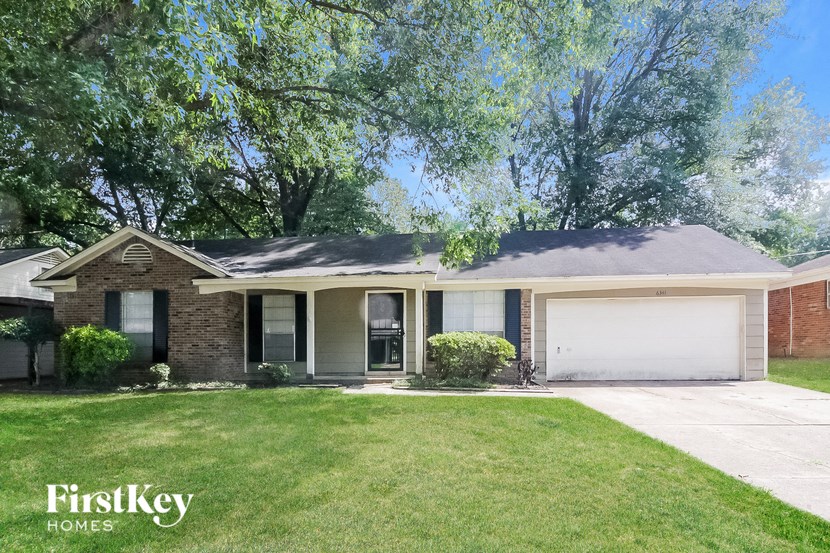 A house with a garage is surrounded by greenery.