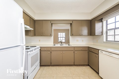 an empty kitchen with white appliances and brown cabinets