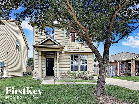 the front of a house with a tree in the yard