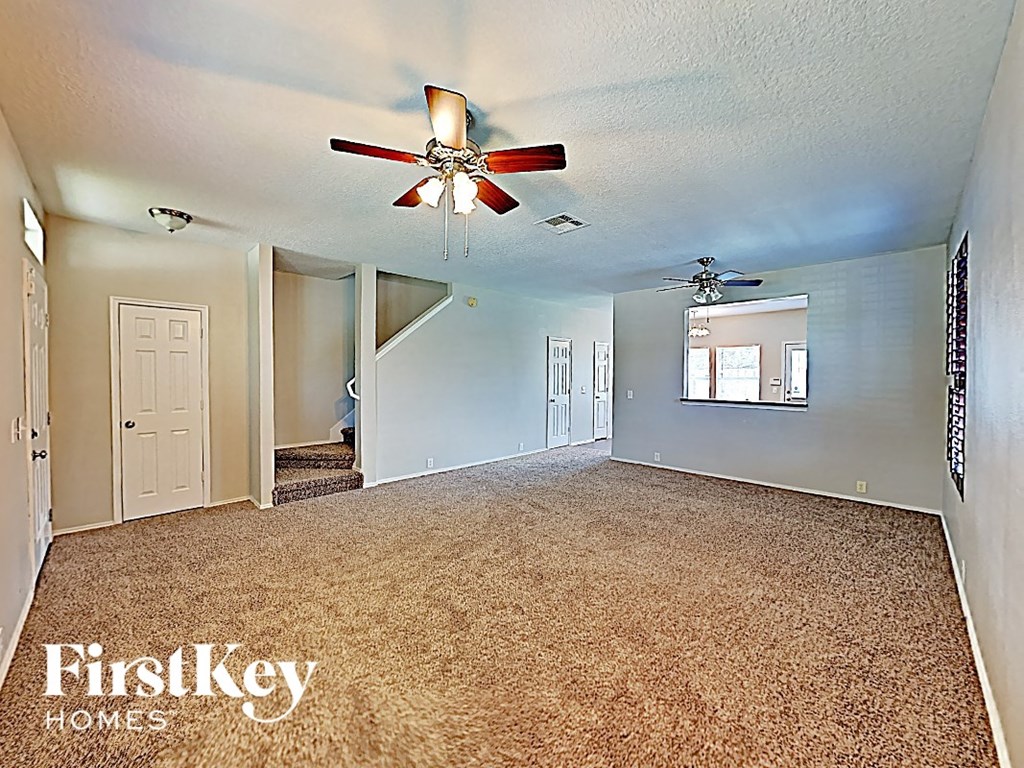 an empty living room with a ceiling fan