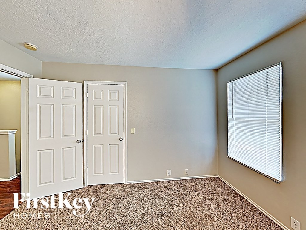 an empty bedroom with white doors and a window