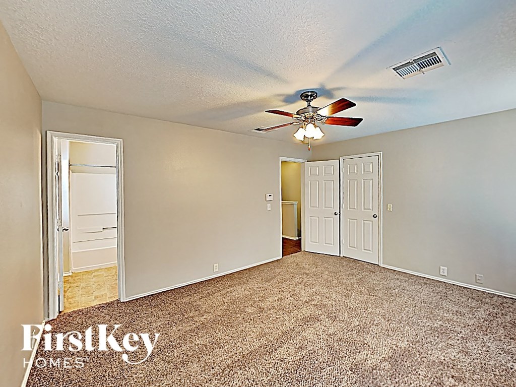 an empty living room with a ceiling fan and a closet