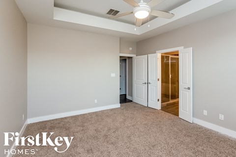 a master bedroom with carpet and a ceiling fan
