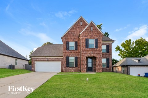 A brick house with a large front yard and a clear blue sky.