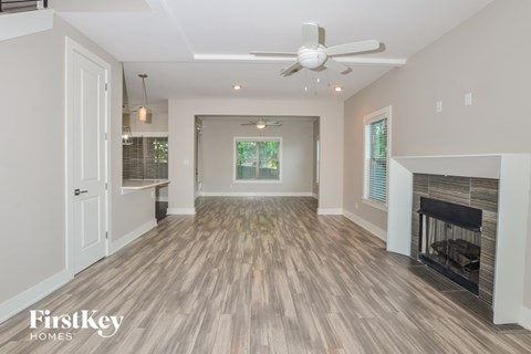 A spacious living room with a fireplace and a ceiling fan.