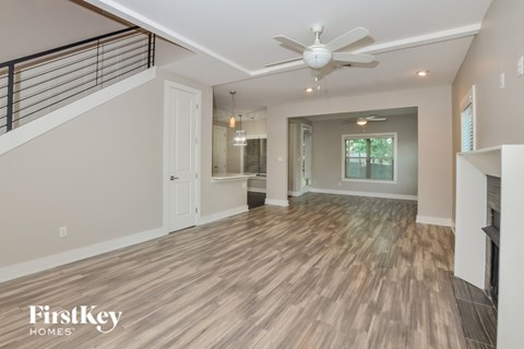 A spacious room with wooden flooring and a ceiling fan.