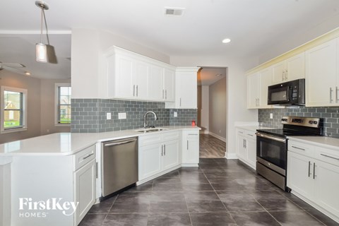 A kitchen with white cabinets and a black stove top oven.