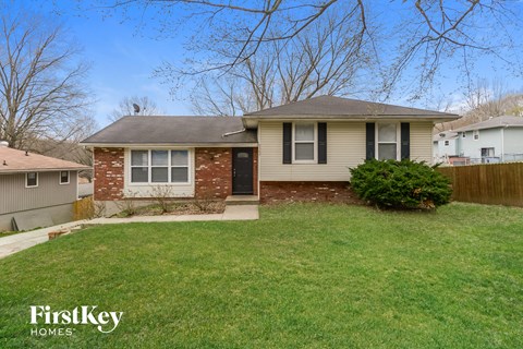 a small brick house with a yard and a fence