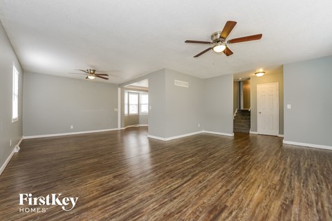 the living room and dining room with wood flooring and ceiling fans