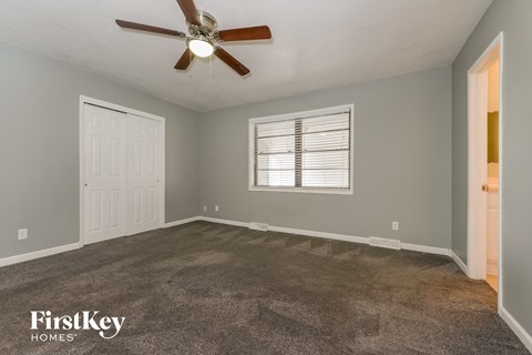 the master bedroom has a carpeted floor and a ceiling fan