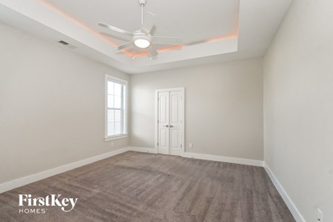 an empty living room with a ceiling fan and a door