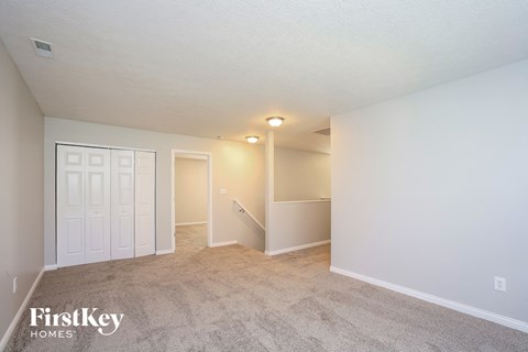 a spacious living room with a carpeted floor and white walls