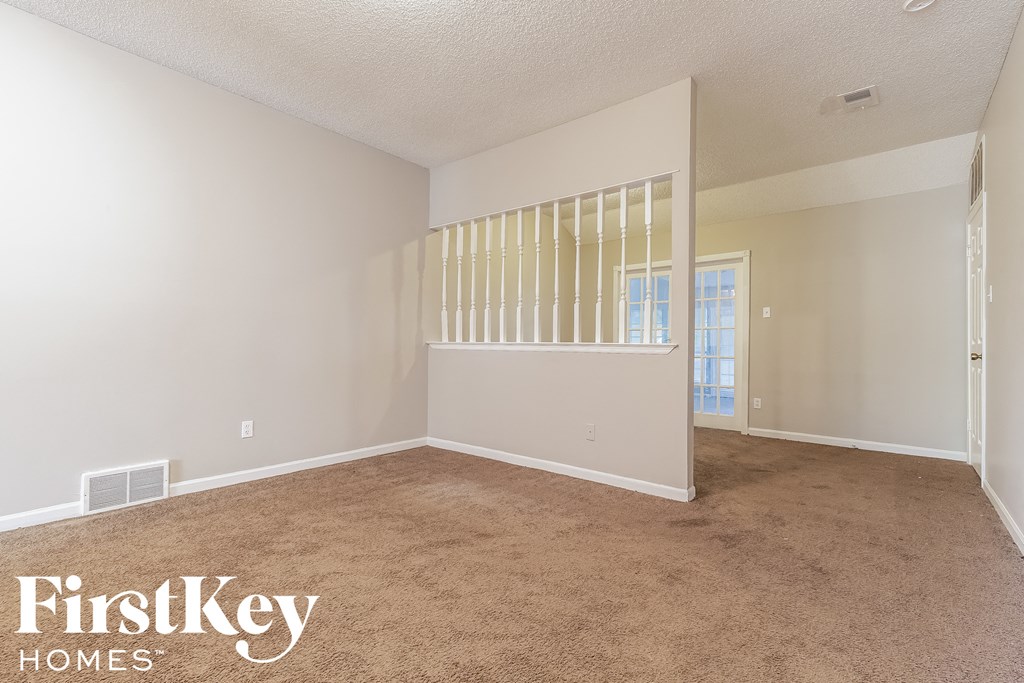 an empty living room with white walls and carpet